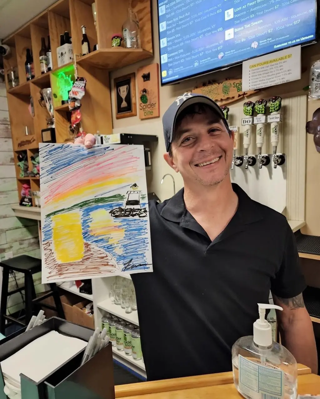 A smiling guest holds up his beach sunset painting