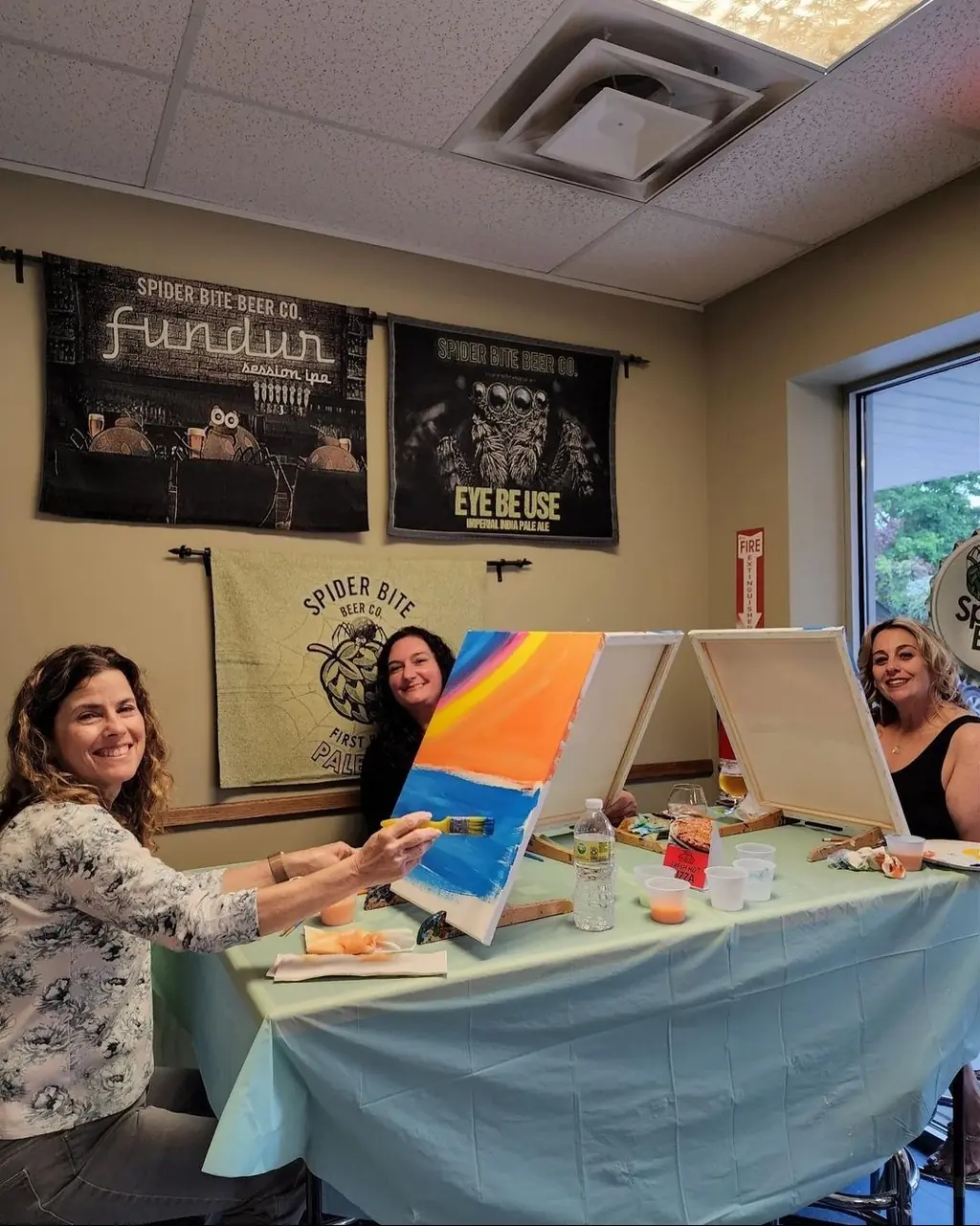 A guest painting a bright sunset canvas at a paint and sip