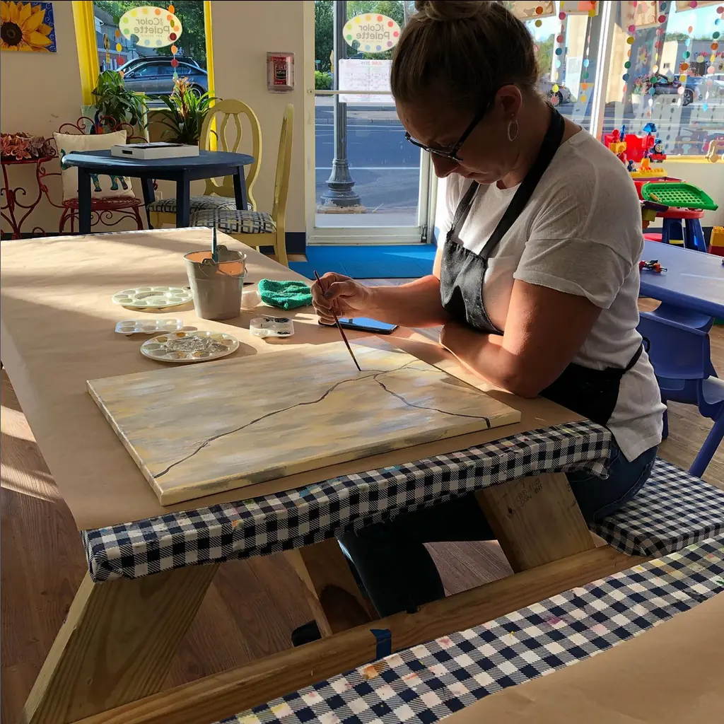 A painter working carefully at a checkered-cloth table