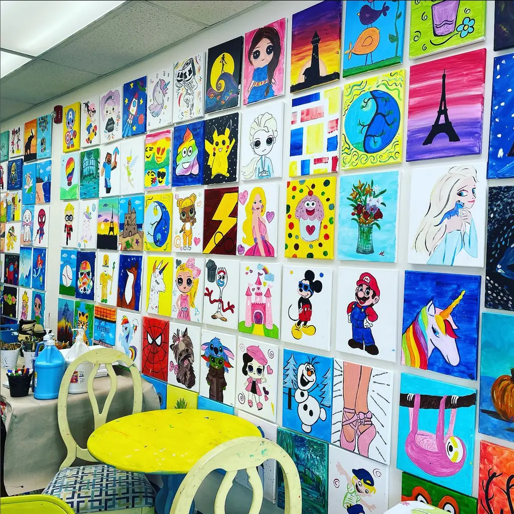 A wall of bright canvases painted by students: rainbows, cartoons and landscapes
