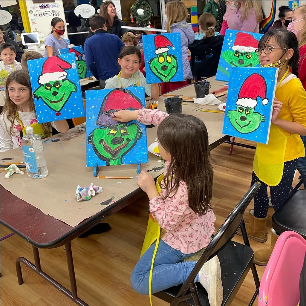 Kids holding up their holiday Grinch paintings