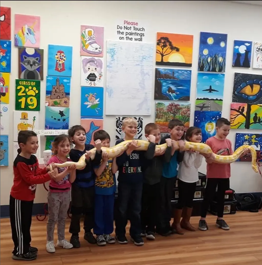 A group of kids with their paintings at the end of class
