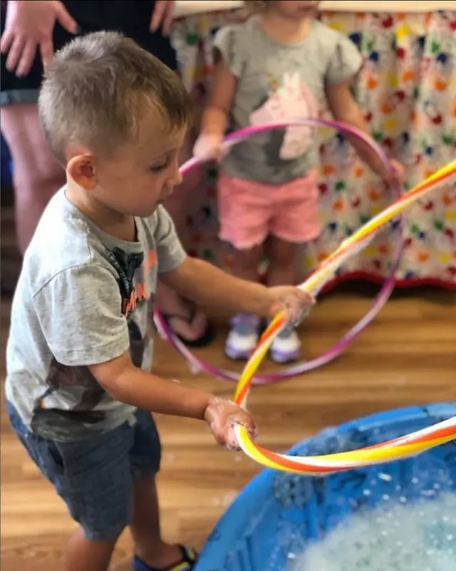 A little one playing with a hula hoop during a party