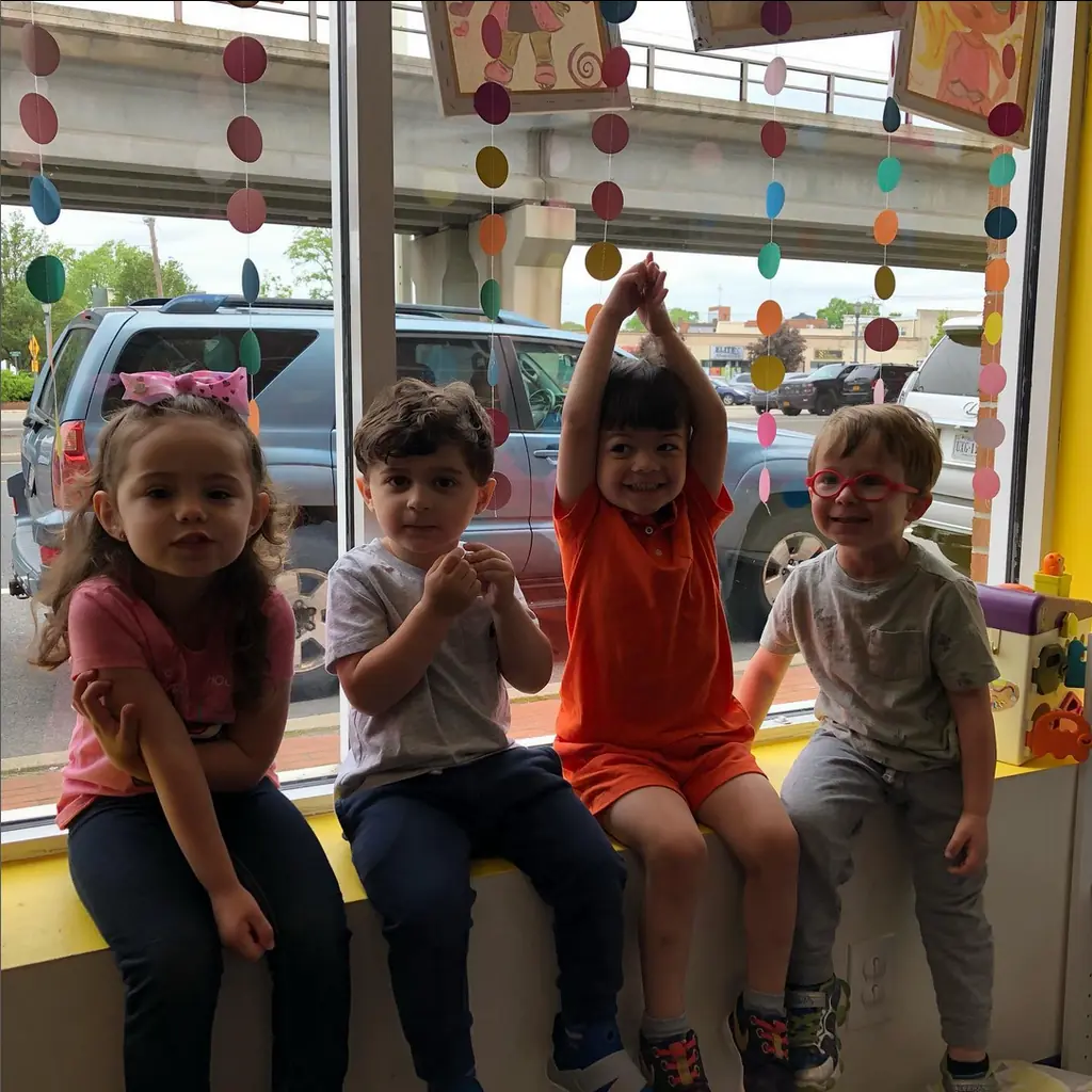 Four happy kids on the studio's window bench, arms in the air