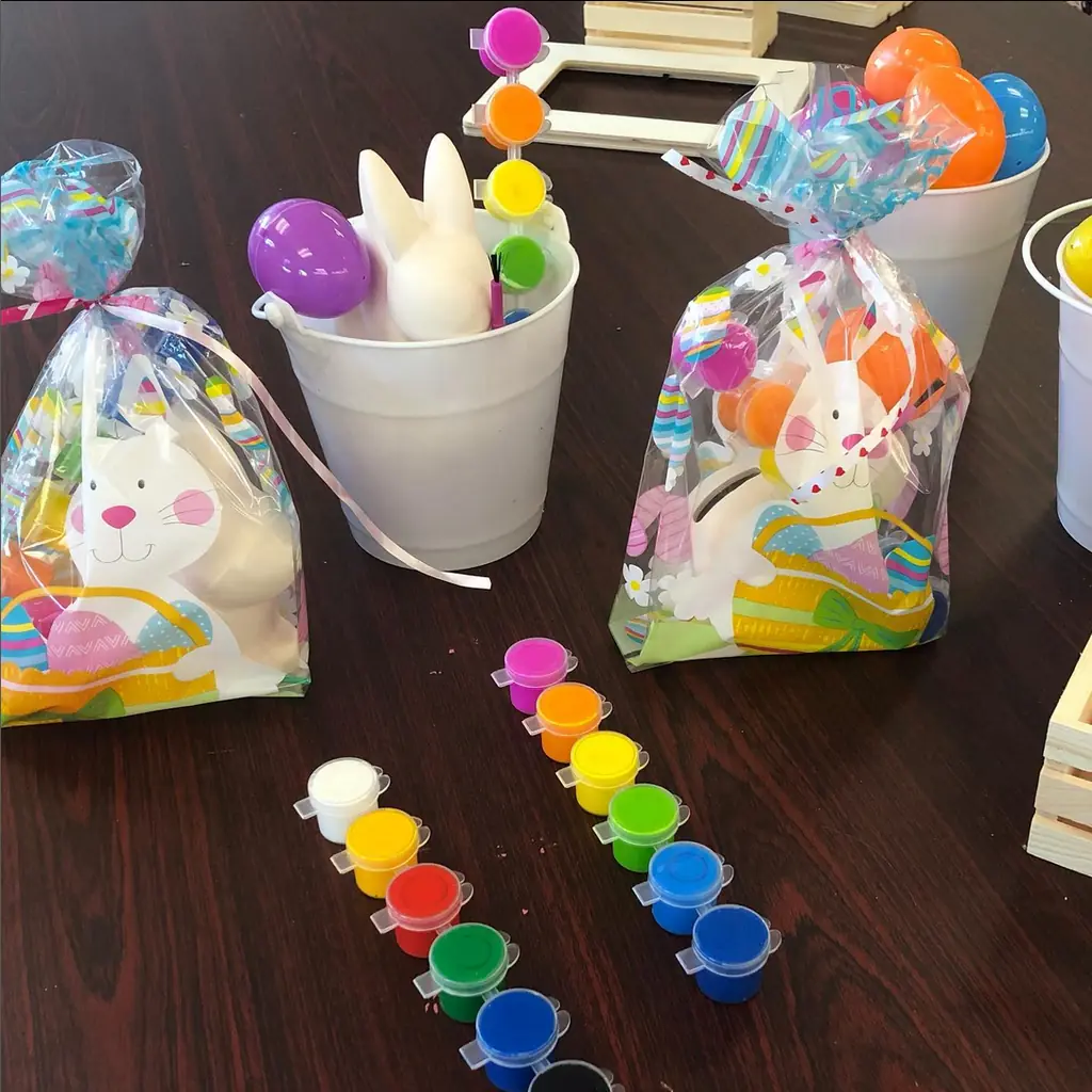 Party favor bags and pots of bright paint on a table