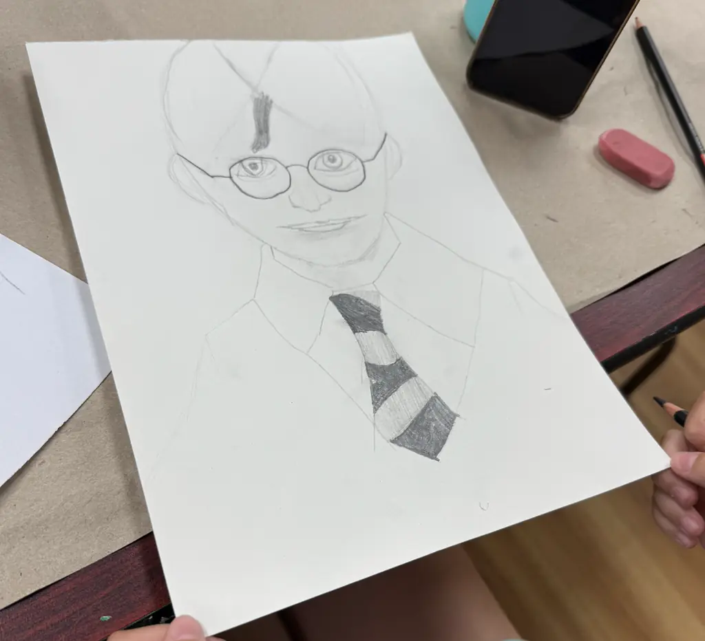 A tween's pencil drawing of a face with glasses, in progress
