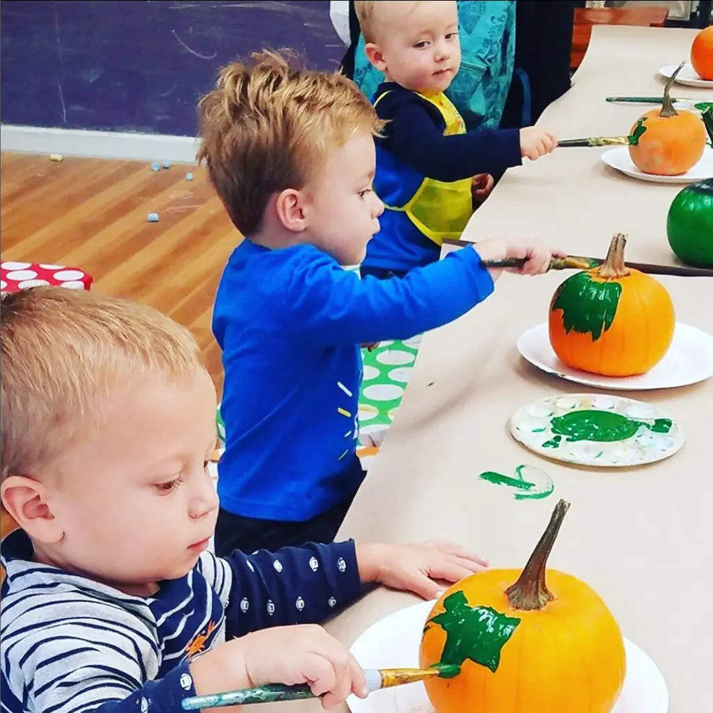 Toddlers painting little pumpkins at a toddler time class